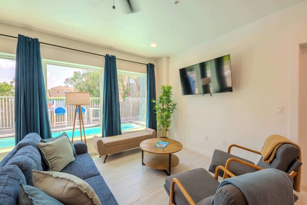 Una sala de estar moderna con un sofá, sillones, una mesa de centro y un televisor montado en la pared.