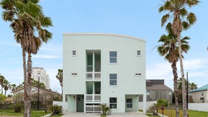 Un edificio de varios pisos con techo plano, rodeado de palmeras.