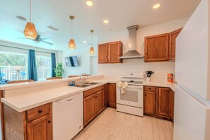 A modern kitchen with wooden cabinets, a built-in oven, and pendant lighting. - Coconut Cove (South Padre Island)