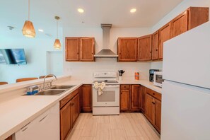 A modern kitchen with wooden cabinets, a stainless steel range hood, a built-in oven, a dishwasher, and a microwave.