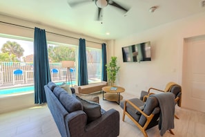 A modern living room with a sofa, armchairs, a coffee table, and a TV on the wall. - Coconut Cove (South Padre Island)