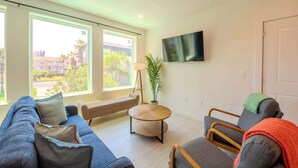 Una sala de estar moderna con un sofá, sillones, una mesa redonda de centro y un televisor montado en la pared.
