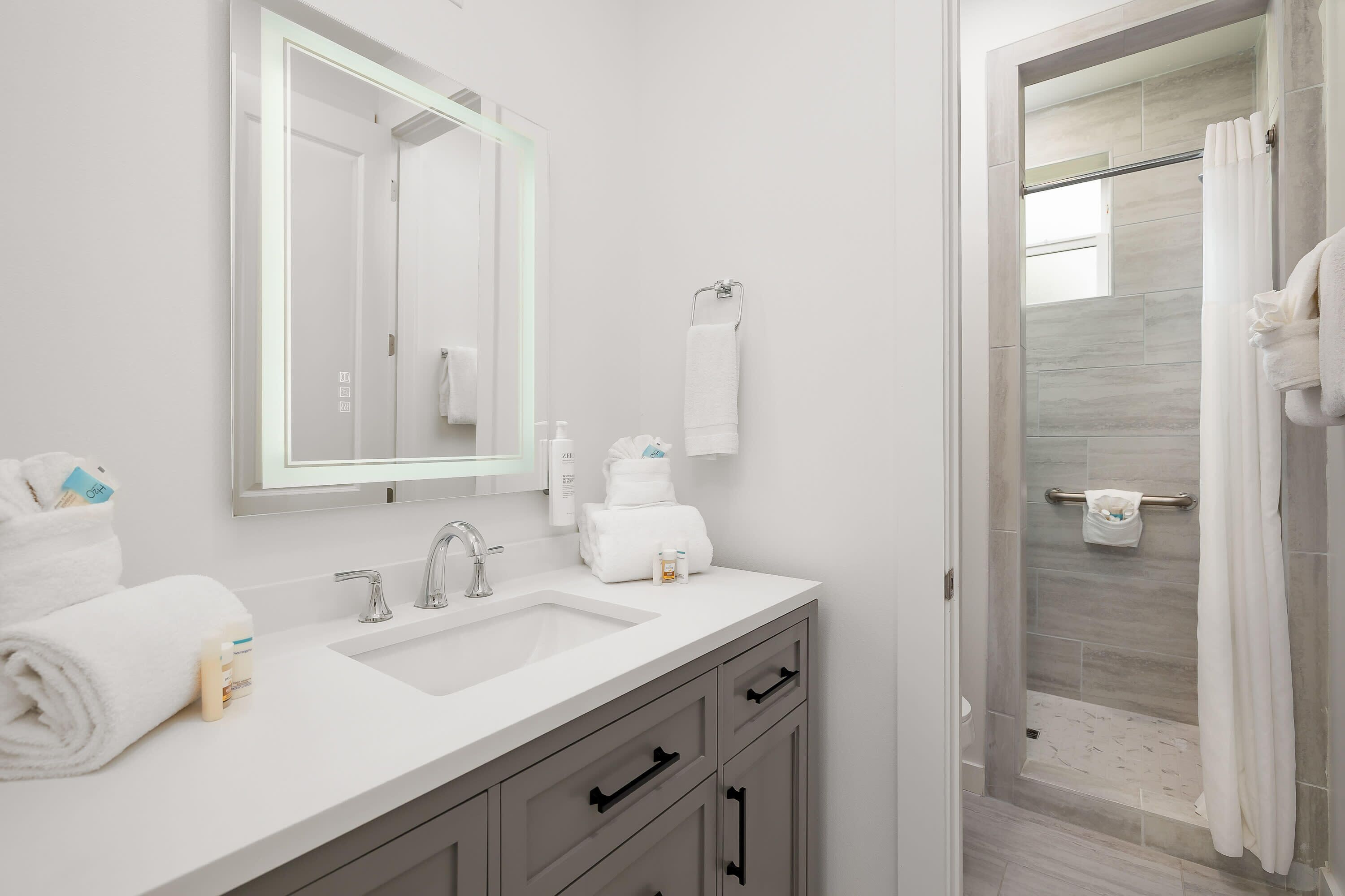 A modern bathroom with a dual sink vanity, a large mirror, and a shower area with a glass door.