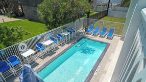 A rectangular swimming pool with a diving board and lounge chairs. - Pineapple Paradise (South Padre Island)
