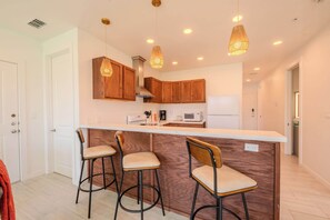 Een moderne keuken met houten kastjes, een centraal eiland met barstoelen en hanglampen.