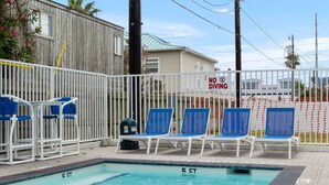 A swimming pool with lounge chairs and a no diving sign. - Pineapple Paradise (South Padre Island)