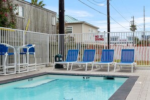 A swimming pool with lounge chairs and a no diving sign. - Pineapple Paradise (South Padre Island)