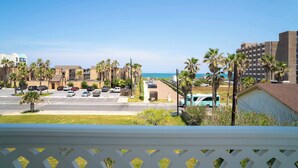A coastal view with a parking lot, buildings, and palm trees. - Pineapple Paradise (South Padre Island)