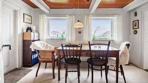 Un comedor con una mesa de madera y cuatro sillas, una araña y vistas a través de las ventanas.