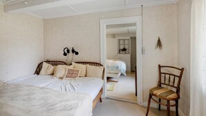 Un dormitorio con cama, una silla y un espejo que refleja otra cama.