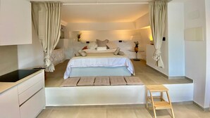 A modern bedroom with a large bed, bedside tables, a small stool, and a built-in desk. - Loft Rodeado de Tranquilidad (Sant Pere de Ribes)
