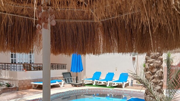 A pool area with blue lounge chairs, a thatched umbrella, and a tiled pool. - VILLA WITH PRIVATE POOL  (Hurghada)