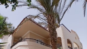 A two-story building with a balcony, a stone staircase, and a seating area with chairs and a table. - VILLA WITH PRIVATE POOL  (Hurghada)