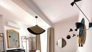 A modern bedroom with a large bed, a desk, a chair, a fireplace, and a mirror. - Maison Familiale Leucate Village Avec Extérieur (Leucate)