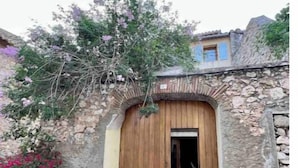 A rustic stone building with a wooden door and a small porch area. - Maison Familiale Leucate Village Avec Extérieur (Leucate)
