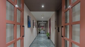 A corridor with glass doors, a marble floor, and potted plants.
