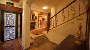A staircase with ornate metal railings, a patterned rug, and a traditional decorative item on a table. - Petra Plaza Hotel (Wadi Musa)