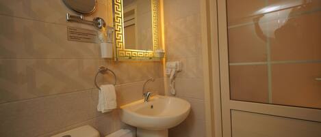 A bathroom with a toilet, sink, and mirror.