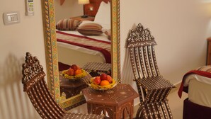A traditional room with a bed, a small table with fruit, and ornate chairs. - Petra Plaza Hotel (Wadi Musa)