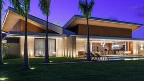 Ein modernes Haus mit Pool, Sitzgelegenheiten im Freien und einem gut beleuchteten Innenraum.