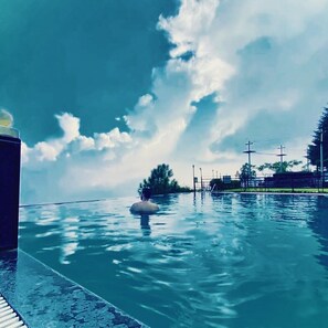 Una piscina con una persona nadando, rodeada por una valla y árboles.