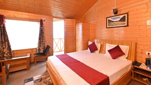 A wooden cabin bedroom with a bed, a chair, a desk, and a window with curtains.