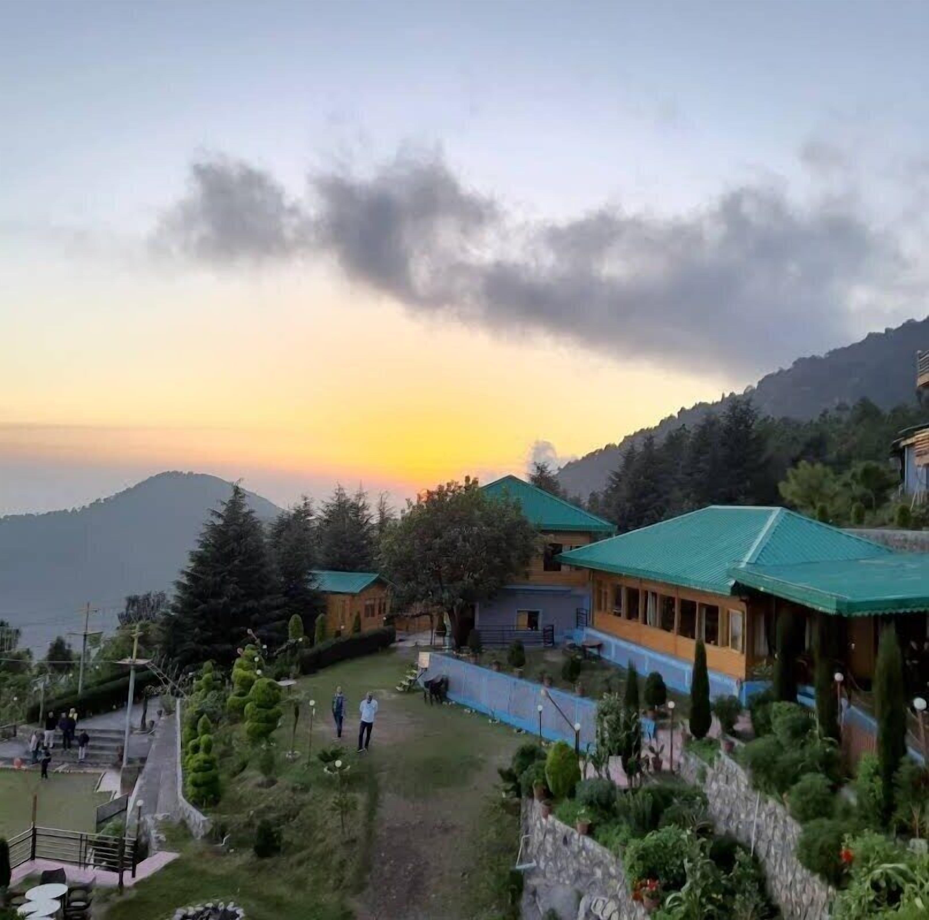 A resort with multiple buildings, a grassy area, and a mountainous backdrop.
