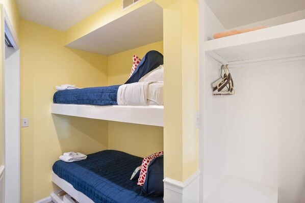 A bunk bed room with two beds, a white door, and a towel rack.