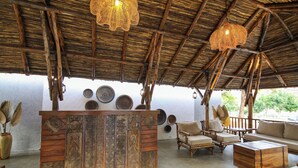 A rustic interior with a wooden reception desk, wicker hanging lights, and a seating area with sofas and chairs. - Toyam by Orchid Hotels (Bhor)