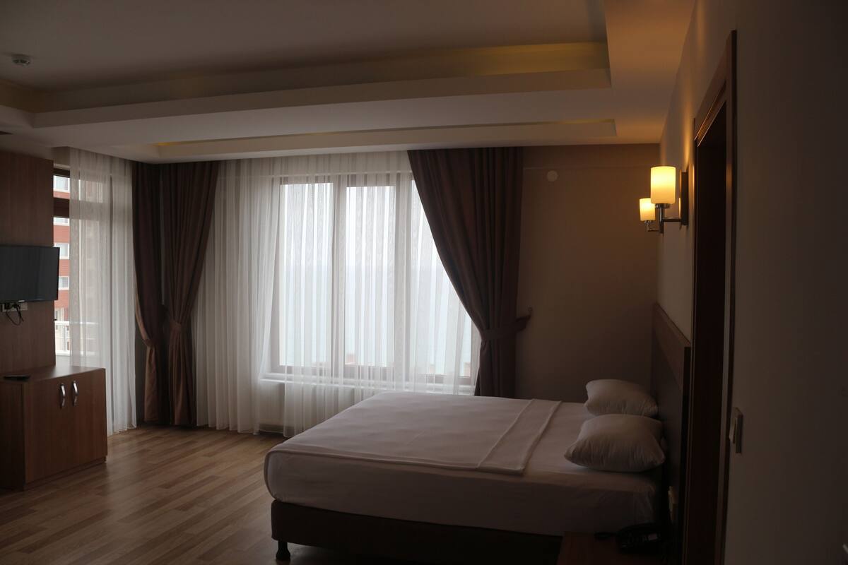 A hotel room with a bed, a TV, a wardrobe, and a window with curtains.