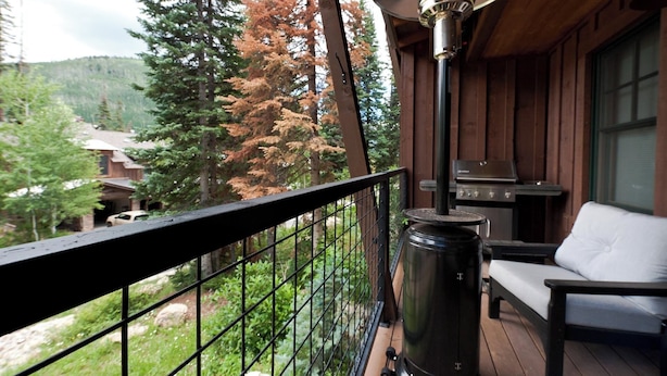 Un balcon avec une balustrade en métal, une lanterne noire, un barbecue et un canapé blanc.