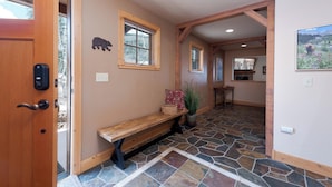 Un couloir avec un banc en bois, un sol en pierre et une décoration en forme d’ours.