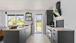 A modern kitchen with a central island, a built-in oven, and a large window providing a view of the outdoors.