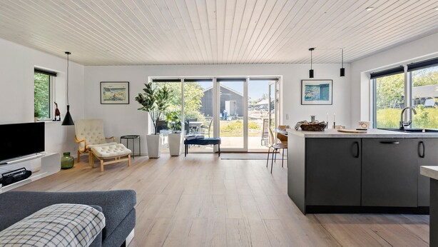 A modern kitchen with a large island, sliding glass doors leading to a patio, and a cozy seating area with a sofa and armchairs.