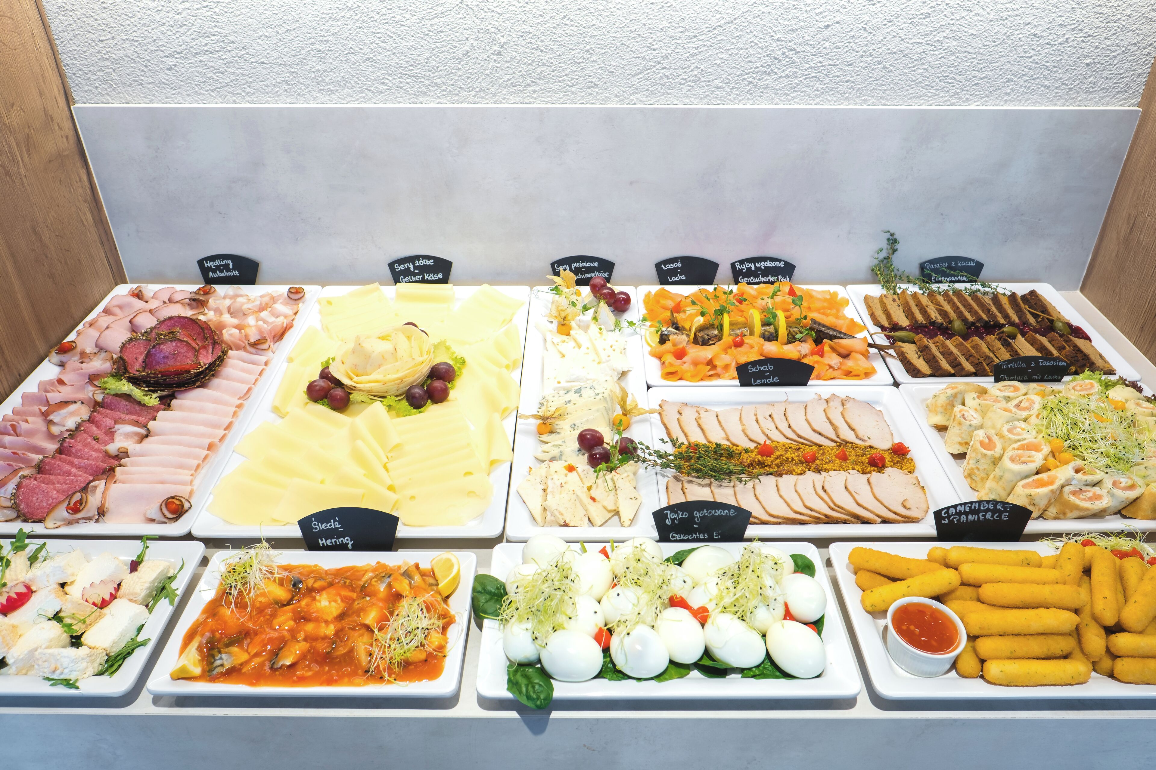 A buffet with various food items including meats, cheeses, and vegetables.