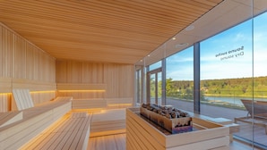 A modern interior with wooden paneling, a seating area, and large windows offering a view of a lake and forest. - Hotel GLAR Conference & SPA (gmina Wolin)