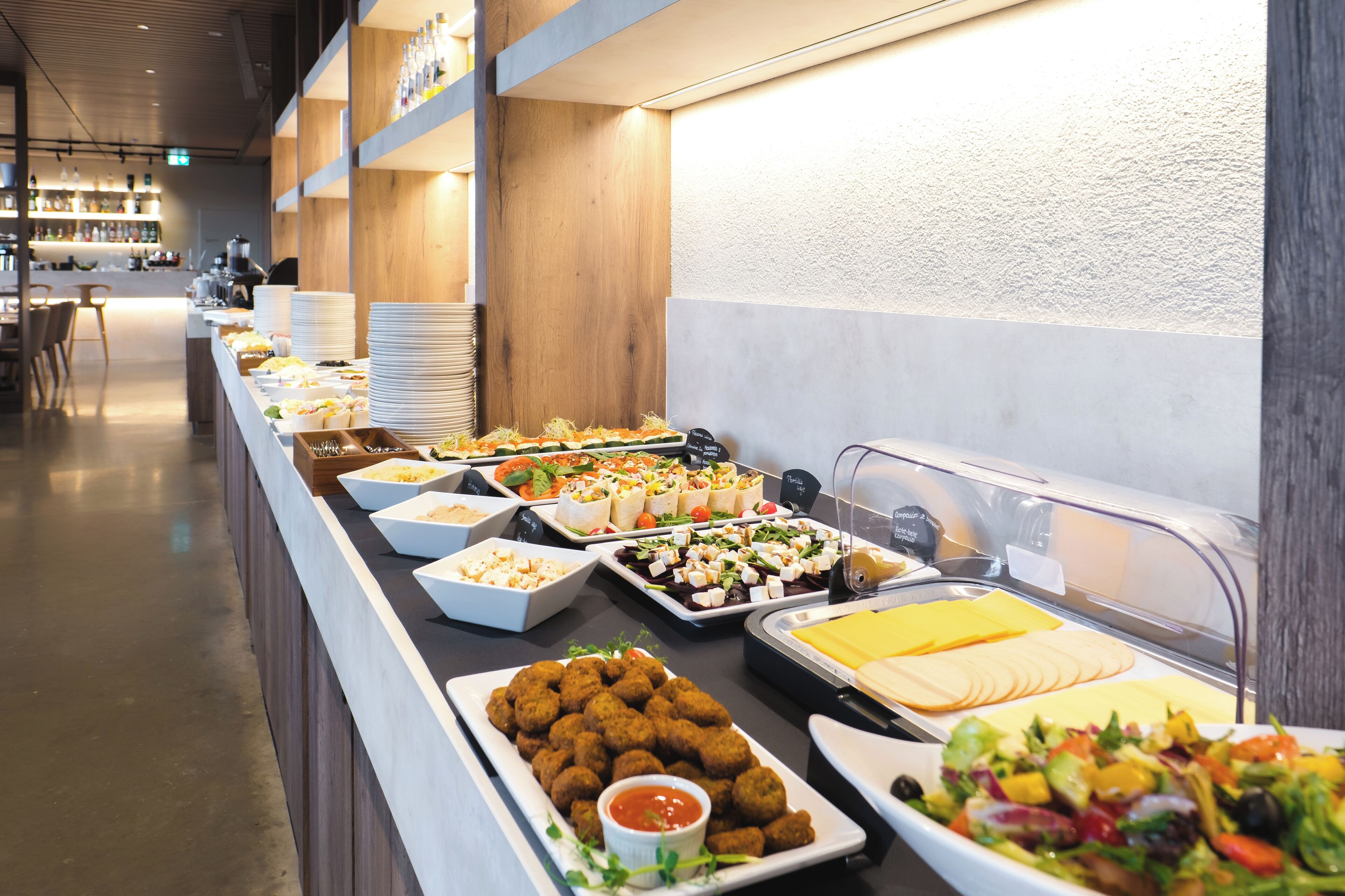Un bufé con diversas opciones de comida, como ensaladas, carnes y aperitivos.