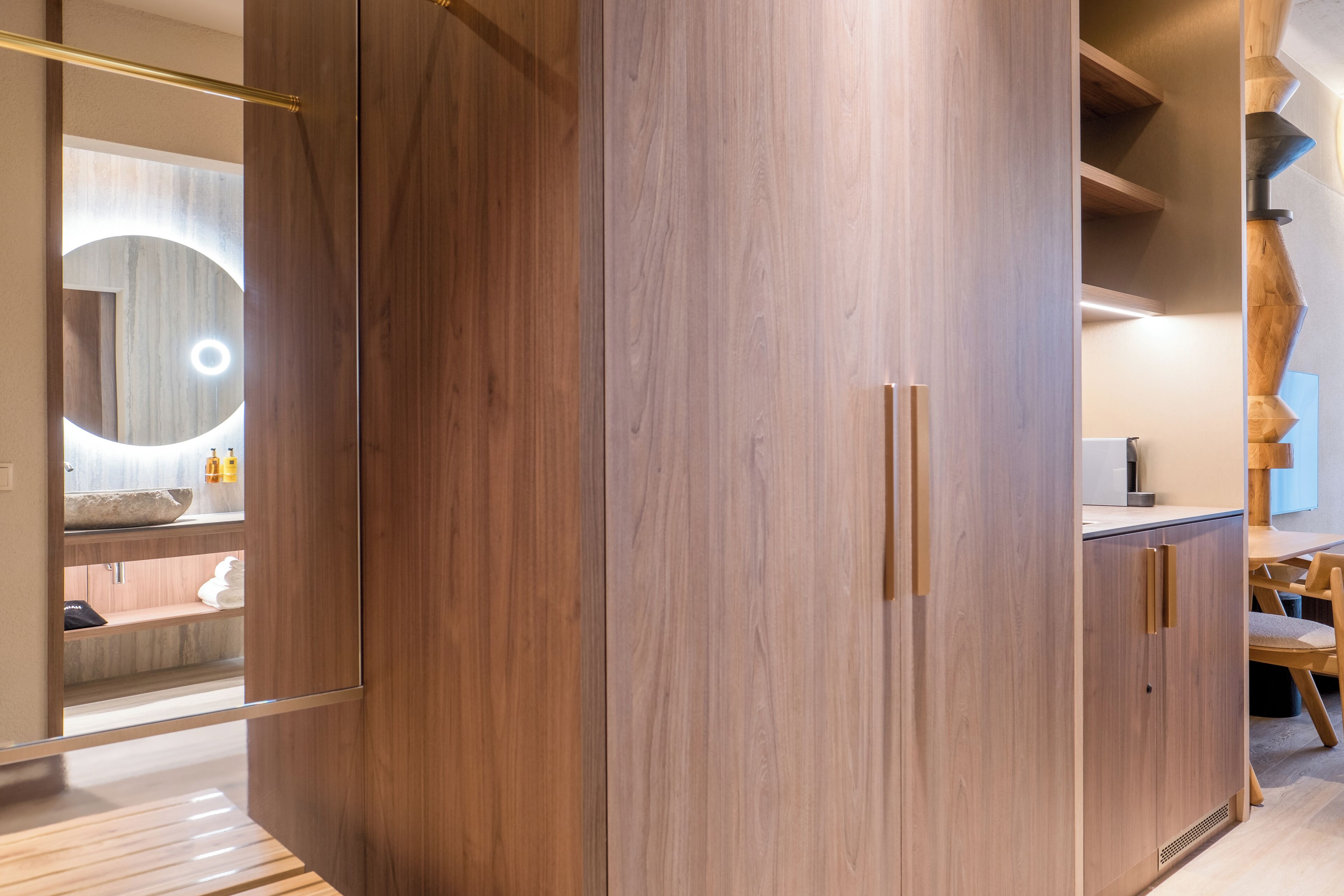 A modern bathroom with wooden cabinetry, a mirror with a circular light, and a wooden vanity.