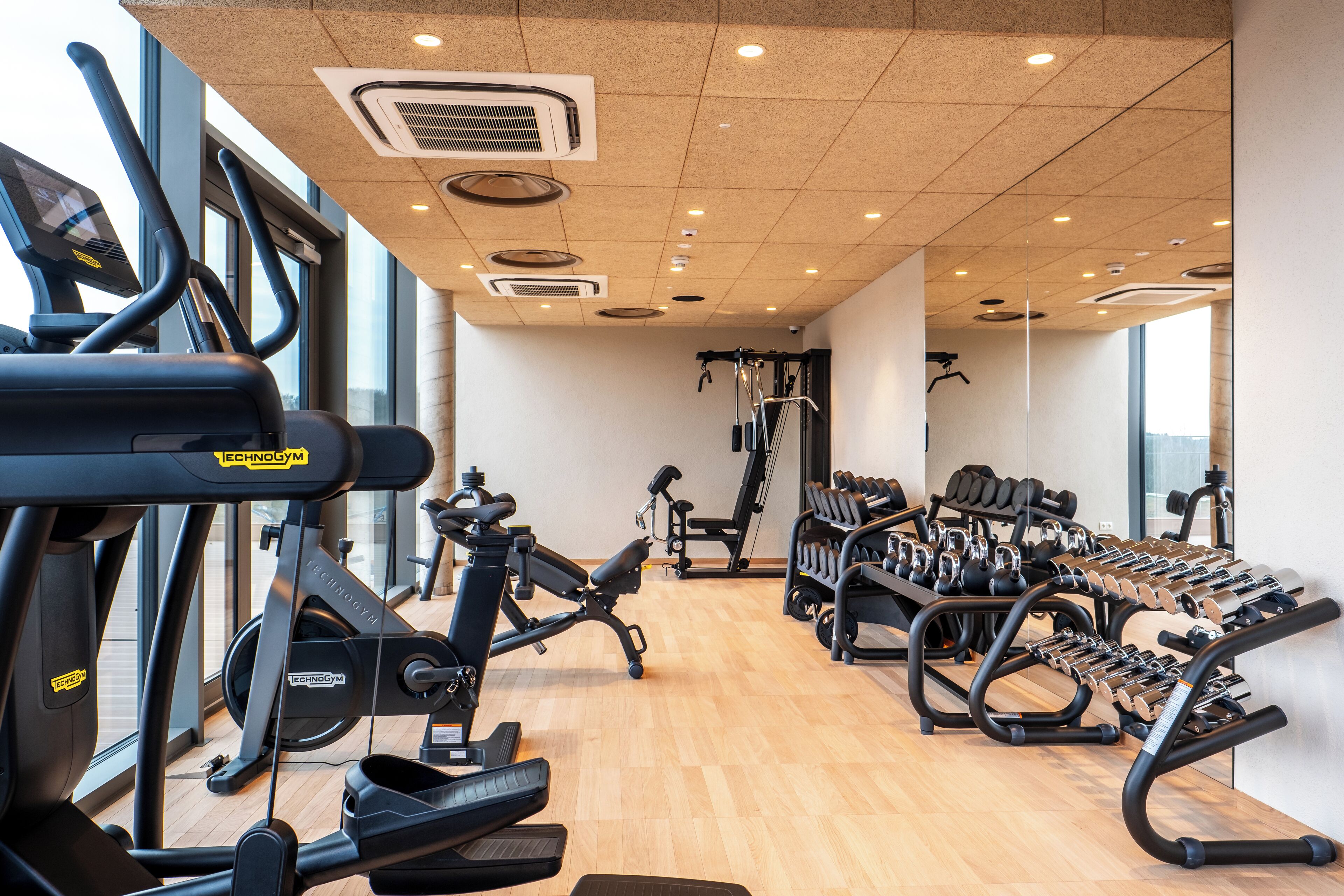 Un gimnasio con máquinas de cardio, mancuernas y bancos de pesas.