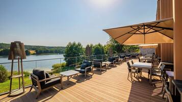 A deck with outdoor seating, a table, and a large umbrella.