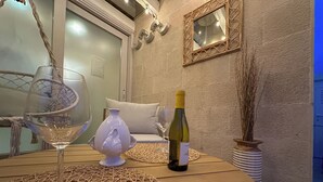 Une pièce chaleureuse avec une table ronde en bois, un vase blanc, une bouteille de vin et un set de table en fibres tressées.