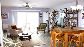 Ein Wohnzimmer mit einer Couch, Stühlen, einem Esstisch und einem Deckenventilator.