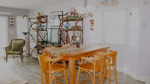 Ein Essbereich mit einem Holztisch und Stühlen, einem Korbstuhl und einem dekorativen Regal mit hängenden Gegenständen.