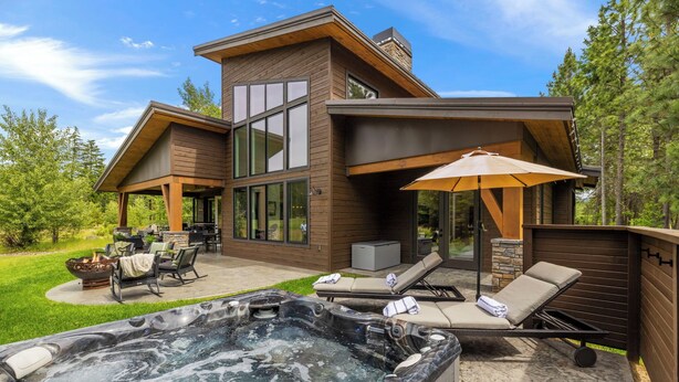 A modern house with a hot tub, outdoor seating, and a large window overlooking a grassy area. - Suncadia's Best Kept Secret | Experience Luxury @ Great Rates (Cle Elum)