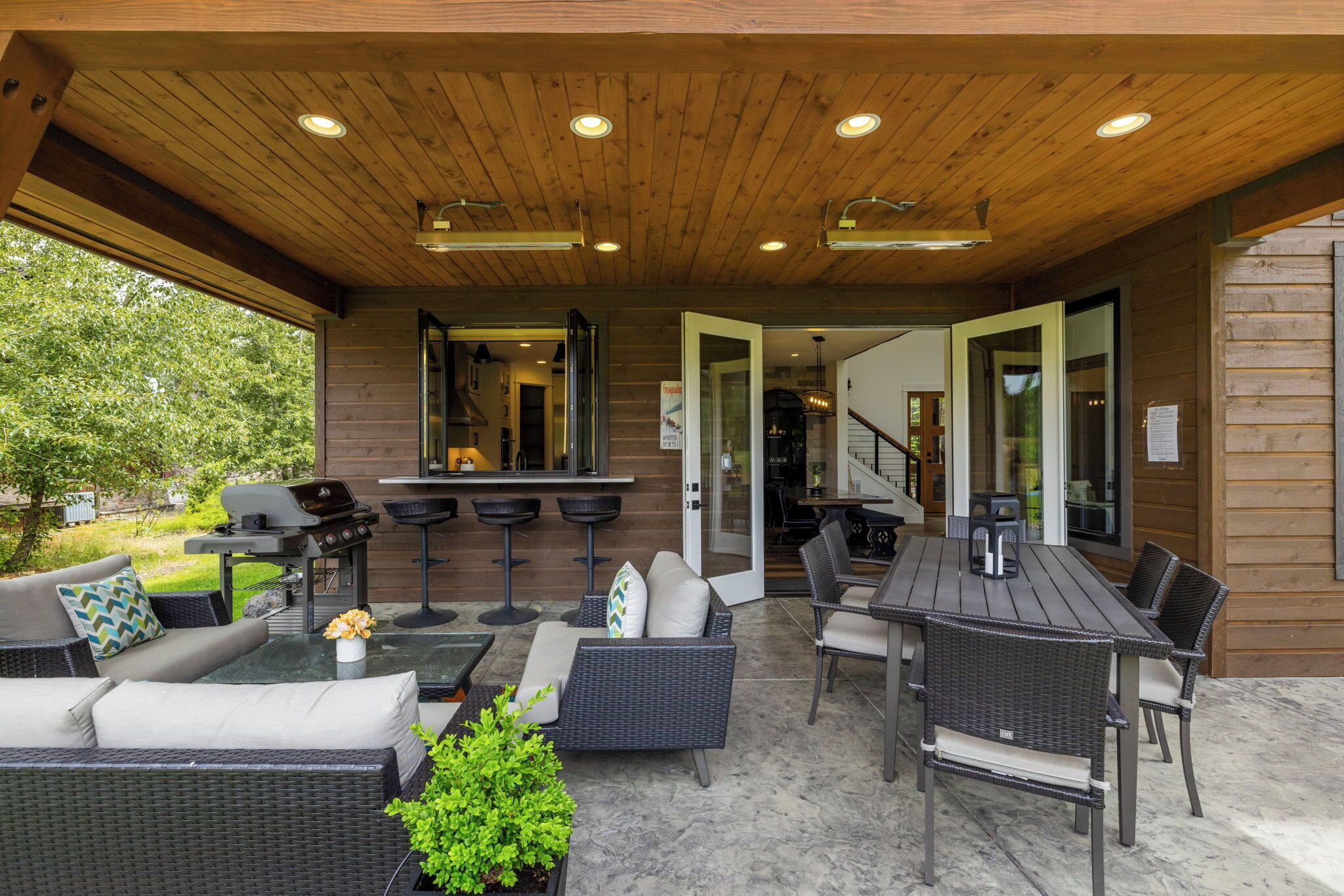 An outdoor patio with a grill, seating area, and a view of the house.