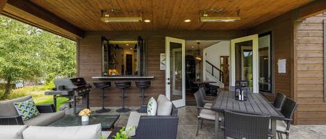 An outdoor patio with a grill, seating area, and a view of the house.