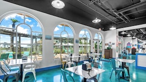 A restaurant with large arched windows, outdoor seating, and a blue floor.