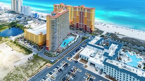 A high-rise hotel with multiple floors, a swimming pool, and a beach view.