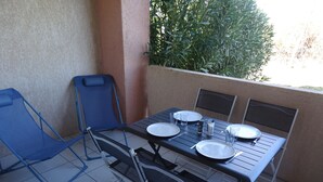 A patio with a table set for four, surrounded by chairs, and a blue folding chair. - la Castagna (San-Nicolao)