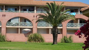 A building with a terracotta roof, multiple balconies with white railings, and a palm tree in the foreground. - la Castagna (San-Nicolao)
